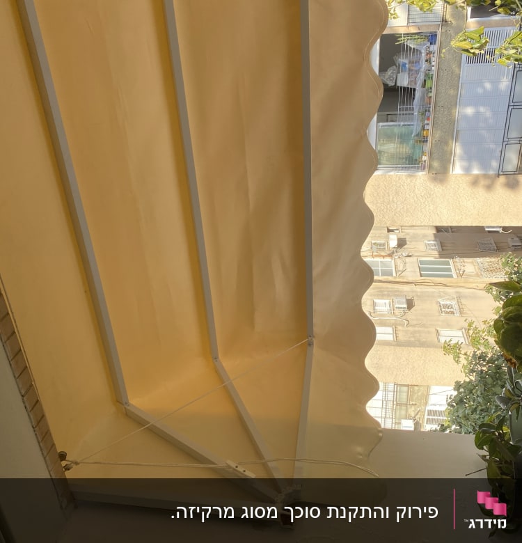 סוכך צהוב עם מסגרת מתכת לבנה במרפסת